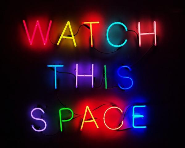 'Watch this space' written in neon lettering