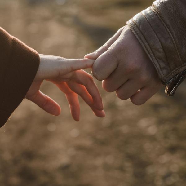 Two hands - one holding the other's finger.