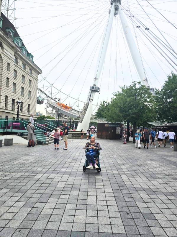 Linda sits in her wheelchair with the London Eye behind her.