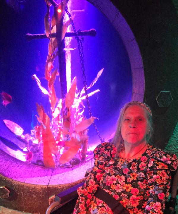 Linda sits in front of a bright coloured display of coral