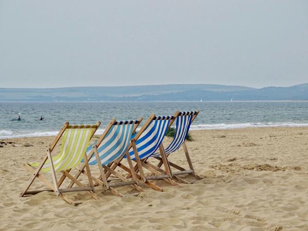 four striped deck chairs on the beach facing the sea