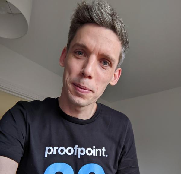 Volunteer James smiles at the camera wearing a Proofpoint t-shirt