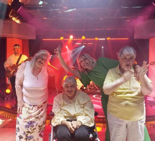 Four people stand dancing at a disco on the cruise ship.