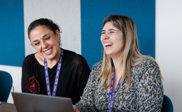 Two RCoA workers smiling and working on a laptop