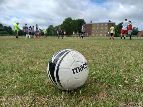 A football sitting on grass in the middle of the pitch.