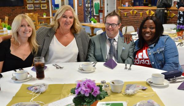 Autism Hampshire staff sit at a table smiling at the camera along with Jeremy from one of our services.
