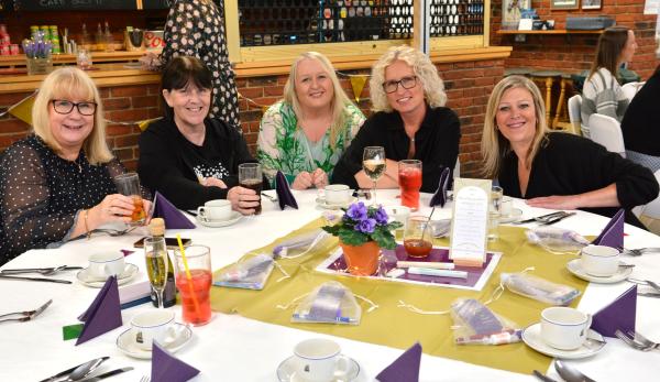 Autism Hampshire staff sit at a table smiling at the camera.