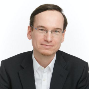 A person wearing glasses (Marcus Kaiser) is smiling at the camera
