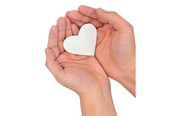 Open palms cup a white heart