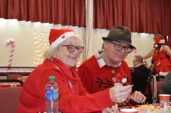 Dressed in festive red sweaters and holiday hats, two party goers enjoying the Christmas party.
