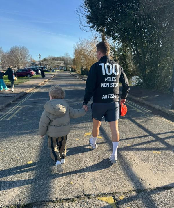 Mike walking with his son holding his hand.